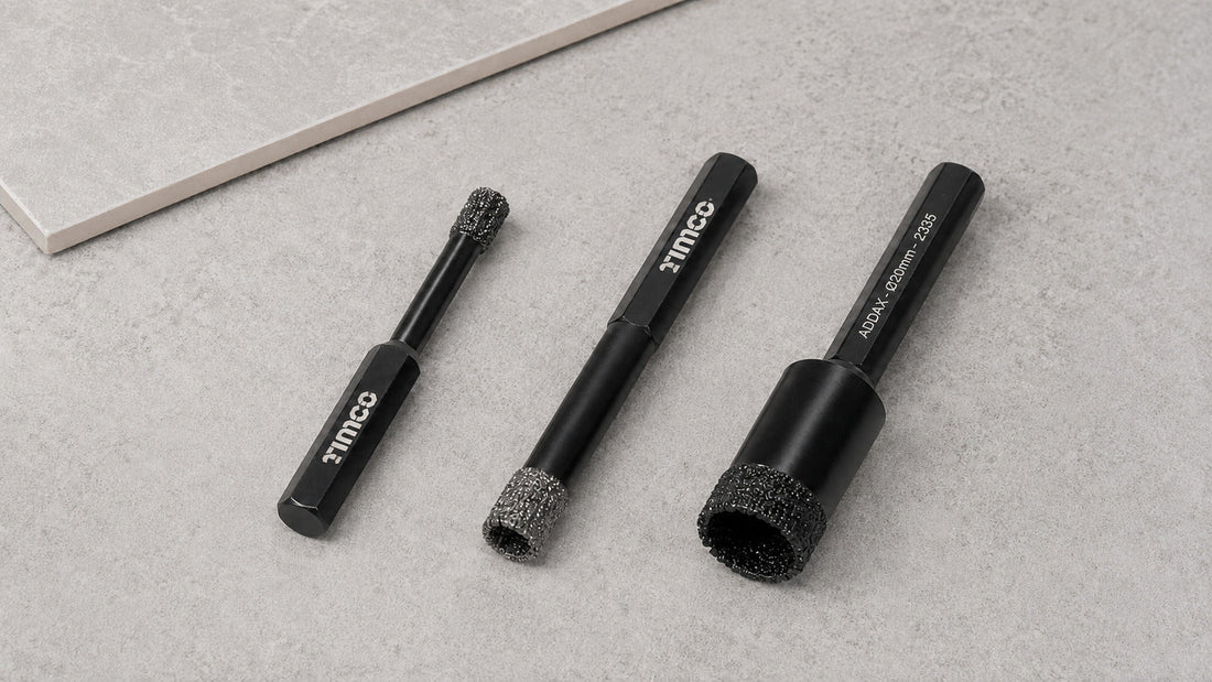 Three TIMCO diamond drill bits in different diameters arranged beside an intact grey porcelain tile sample.