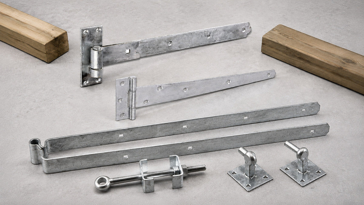 Hot-dip galvanised straight band, tee and adjustable fieldgate hinge systems arranged separately on a trade workbench